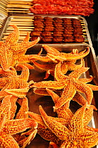 Starfish next to butterfly pupae on skewers. Open-air food market in central Beijing, China.