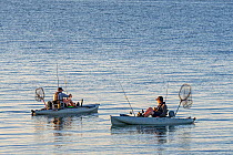 Two sea anglers fishing from pedal drive kayaks at sunset, Brittany, France, September