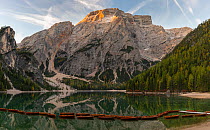 Rental rowboats tied together and first light on Croda del Becco mountain. Lago di Braies, Dolomites, Italy, October 2019.