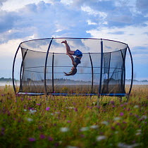 Girl doing a backward flip on a trampoline on a misty evening, Tartumaa county, Southern Estonia. Model released