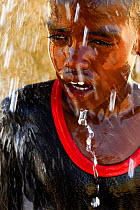 Boy takes a shower with the water from an artificial well in the Sahara desert, northern Chad. September 2019.