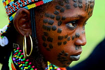 Girl from Wodaabe nomadic tribe with traditional scarifications / markings on face. Attending Gerewol festival, a gathering of different clans in which women choose a husband. Chad, Sahel, Africa. 201...