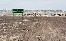 Dirt track road through Skeleton Coast with signs including sign to Hentes Bay and speed limit sign. Namib Desert, Namibia. 2016