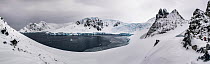 Rocky outcrops along snow covered coast of Orne Harbour, panorama. Antarctic Peninsula, Antarctica. December 2019. Digitally stitched image.