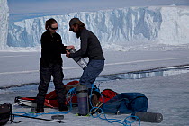 Scientists preparing light trap fishing gear next to a tide crack, Dumont d&#39;Urville station, Antarctica, December 2016.