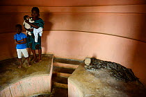 Woman and children standing close to captive African rock pythons (Python sebae) in Temple of Pythons / Dangbe Temple. A voodoo cult dedicated to the python, Ouidah, Benin, 2020.