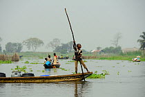 Tofinou boy transporting plastic containers in boat on Lake Nokoue, Oueme River Delta. Ganvie, known as African Venice, Benin, 2020.