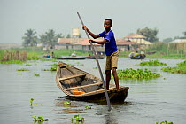 Tofinou boy punting boat on Lake Nokoue, Oueme River Delta. Ganvie, known as African Venice, Benin, 2020.
