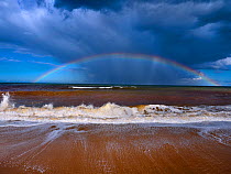Autumn high tides with stormy skies and rainbow over the sea, Walcott, Norfolk, England, UK, September.
