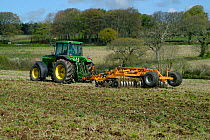 John Deere tractor with a Simba power disc harrow cultivating set-a-side field before planting with maize in Devon, April