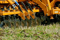 Tractor with a Simba power disc harrow cultivating set-a-side field before planting with maize in Devon, April