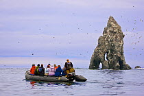 Ecotourists view a seabird colony on off-shore rocks in the Bering Sea near Verkhoturova Island, Russia. The nesting species include common and Brunnich&#39;s guillemots (Uria aalge and Uria lomvia ar...