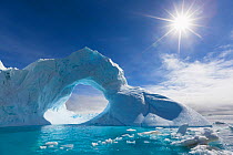 Iceberg Arch and sunstar along the Antarctic Sound, Antarctica.