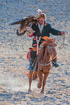 Eagle hunter on horse with female golden eagle (Aquila chrysaetos) at the Eagle Hunters festival, nearing finish line. Near Ulgii Western Mongolia. Medium repro only