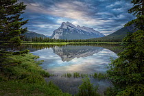 Snow capped Mount Rundle and surrounding forests reflected in Vermillion Lakes. Banff National Park, Alberta, Canada. June 2018.