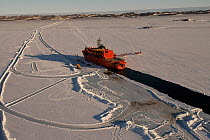 Aurora Australis Resupply vessel moored in fast ice in front of Davis station, cargo is being discharged by ice road. Two CASA planes parked next to the ship, Antarctica November 2005