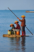 Fishermen of Shi Ma Jiao harbour using styrofoam blocks as rafts to reach their fishing boat at high tide, Guangdong province, China November 2015