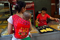 Mother and baby out shopping and walking in the street, Old Julong village, Guangzhou, Guangdong, China November 2015.