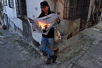 Conceptual image of Man reading 'Hot news', with newspaper on fire. Zhan Jiang city, Guangdong, China November 2015.