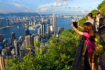 Tourist looking down at Victoria Harbor from Victoria Peak, Hong Kong, China, June 2016.