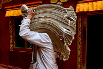 Person carrying printed material at Gonchen Gompa / Derge Monastery, home to one of the largest papermaking and printing factories of Buddhist prayers. Derge, Garze Tibetan Autonomous Prefecture, Sich...