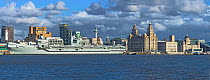 HMS Prince of Wales aircraft carrier moored at the Liverpool Pierhead on the River Mersey with the Three Graces building on the right, Liverpool, England, UK, March 2020.