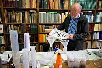 Entomologist with sample of insects caught in malaise trap, refernce books in background. Long-term monitoring has revealed a 75% decline in insect biomass over 27 years. Entomological Society Krefeld...