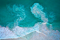 Waves crashing on beach and carrying sediments back out to sea, aerial view. The Bahamas.