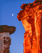 Sandstone pinnacles with dawn&#39;s red light and crescent moon setting, Colorado Plateau, Utah, USA.