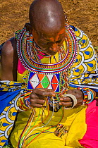 Maasai woman creating traditional bead jewellery. Maasai Mara National Reserve, Kenya. 2007.