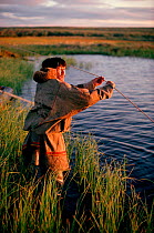 Sasha Serotetto, a Nenets reindeer herder, sets a fishing net on a tundra pond. Yamal. Siberia. Russia. 1993.