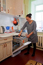 Valya Khudi,a Nenets woman, unloading the dish washer in the modern kitchen of her family&#39;s apartment in Yar-Sale, Yamal, NW Siberia, Russia. 2017.