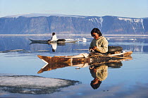Inuit hunter, Qitdlaq Duneq, in his skin kajak amongst icebergs with reflection. Qeqertat, Thule, Greenland. 1977