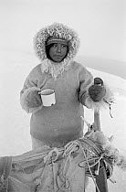 Otto Simigak with a mug of tea during a break on a hunting trip in light snow. Siorapaluk, Northwest Greenland.1977.