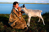 Albina Rocheva, a Nenets girl, kisses one of her family&#39;s pet reindeer calves. Nadym Tundra, Yamal, Western Siberia, Russia. 2000