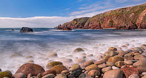 Pebbles on shoreline, cliffs along coast beyond. Bloody Foreland, Knockfola, County Donegal, Republic of Ireland. June 2020.