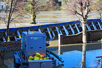 Water pump with flood barrier beyond holding back flooded River Severn. After Storm Ciara and Storm Dennis, the wettest February recorded in the UK. Ironbridge, Shropshire, England, UK. February 2020.