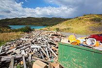 Skip and pile of rubbish from a tourist lodge, Lake Pehoe in background. Torres del Paine National Park, Patagonia, Chile. January 2020.