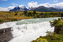 Cascada Paine waterfall, mountains and Torres del Paine peaks in background. Torres del Paine National Park, Patagonia, Chile. January 2020.