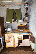 Trousers drying above kitchen stove, Station W, former British scientific research station evacuated in 1959. Detaille Island, Graham Land, Antarctica. 2020.
