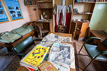 Magazines on table and clothes drying over stove in Station W, a former British scientific research station evacuated in 1959. Detaille Island, Graham Land, Antarctica. 2020.
