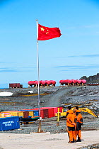 Workers standing near Chinese flag at Great Wall Station, Chinese research base, King George Island, South Shetland Islands, Antarctica. January 2020.