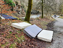 Mattreses fly tipped and illegally dumped in car park. White Moss, near Ambleside, Lake District National Park, England, UK. February 2020.