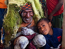 Elderly man wearing Lichen headdress with boy at welcome ceremony, portrait. Kiowe, Eastern Highlands, Papua New Guinea. 2019.