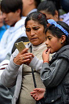 Children visiting Monarch butterfly reserve. Teacher and child looking at images of butterflies on mobile phone, Sierra Chincua Sanctuary, Mexico.
