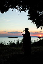 Priest standing beside Lake Tana at sunset. Mandaba Medhane Alhem Orthodox Monastery, near Gorgora, Ethiopia. 2018.