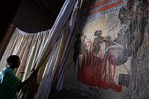 Deacon revealing mural paintings in sanctum of Debre Sina Orthodox Church. Near Gorgora, Ethiopia. 2018.