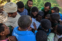 NABU staff member showing birds in guide book to people of Wagira Maryam church. In church forest, a forest fragment surrounding the orthodox church, remaining intact in a largely deforested landscape...