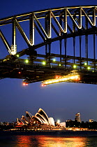 Sydney Opera House and skyline, viewed at dusk under Sydney Harbour Bridge. New South Wales, Australia. 2008.