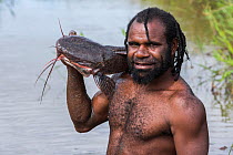 Dani tribe fisherman with large catfish, Budaya village, Suroba, Trikora Mountains, West Papua, Indonesia. October 2020.